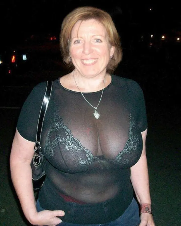 Femme aux cheveux blonds courts en chemisier noir transparent, souriante de nuit