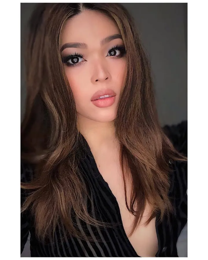 Femme aux cheveux bruns, portant un haut noir à dentelle, en gros plan, avec un regard direct