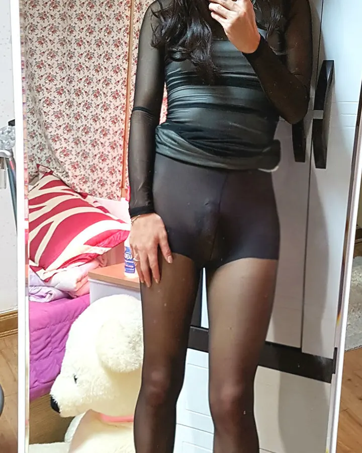 Femme trans aux cheveux bruns, en tenue noire, debout sur un escalier industriel
